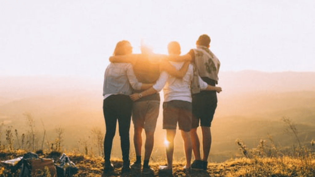 Gruppe junger Leute bei Sonnenuntergang in den Bergen