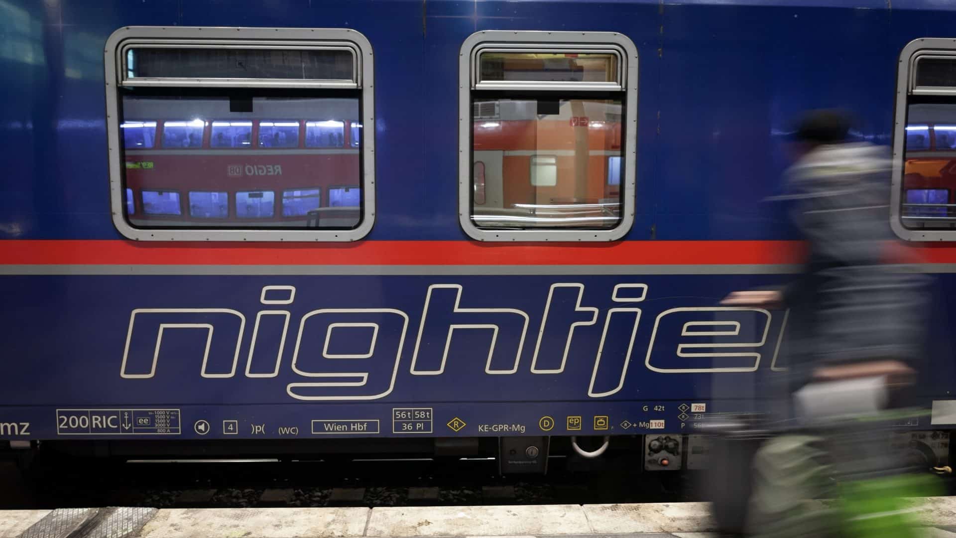 Selective Blur On The Nightjet Logo On An Overnight Train To Austria In Koln Hbf With Blur Of A Passenger Rushing. NightJet Is A Train System Of Austrian Railways.
