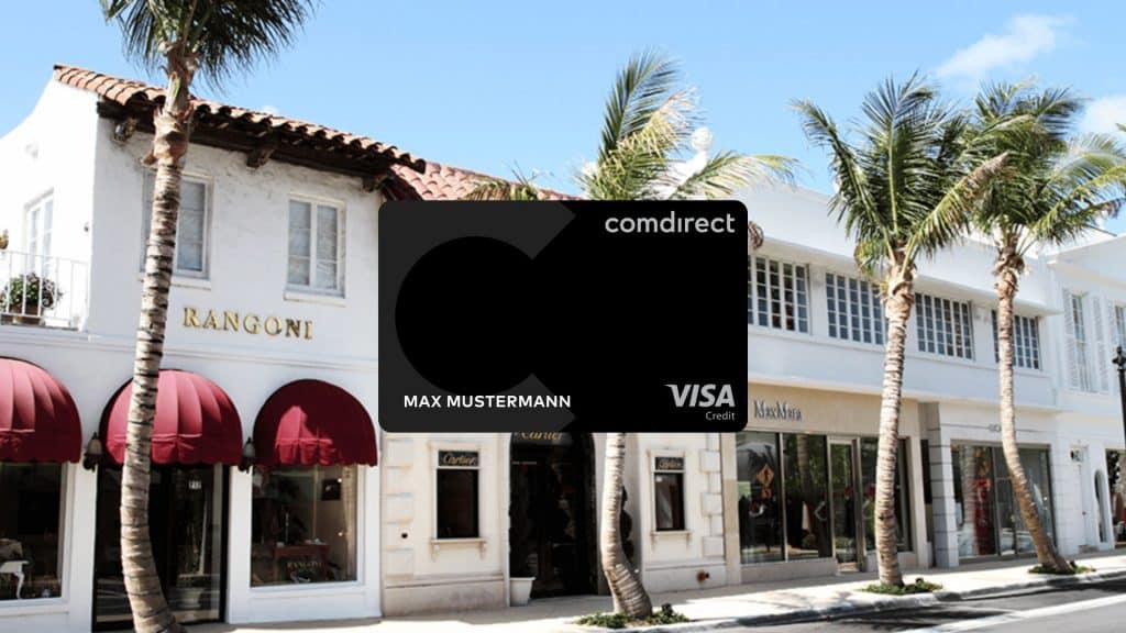 Comdirect Kreditkarte im Vordergrund, im Hintergrund weisse Haeuser und Palmen