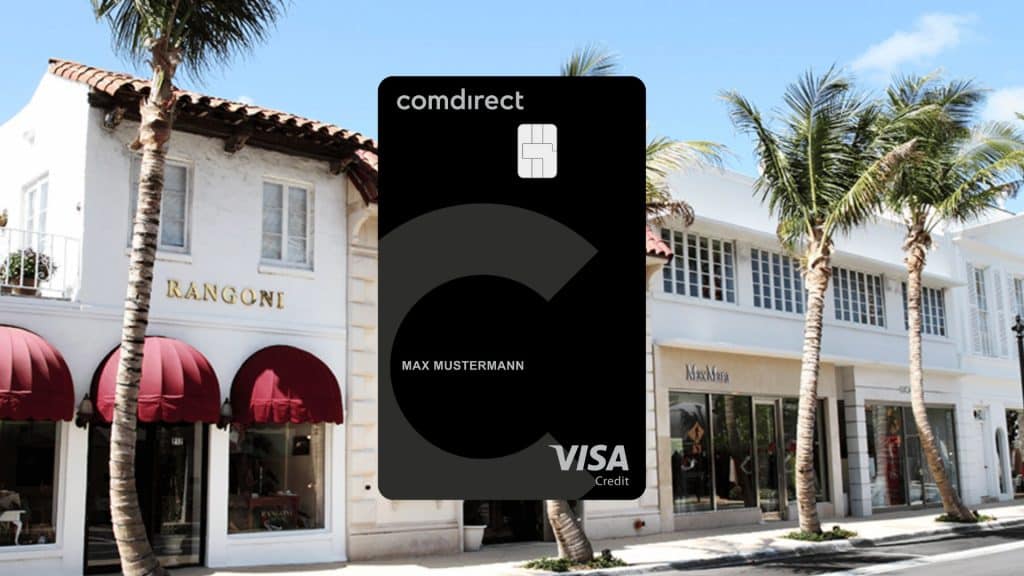 Schwarze comdirect Visa Kreditkarte vor einer Einkaufsstraße mit Palmen