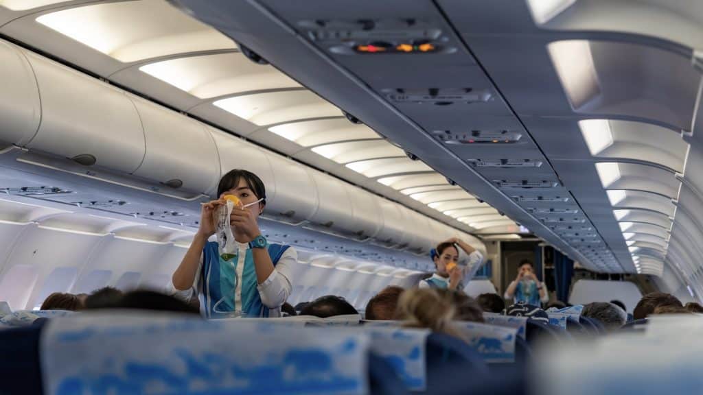 Flight Attendants Demonstrate The Proper Use Of Oxygen Masks Before Flight