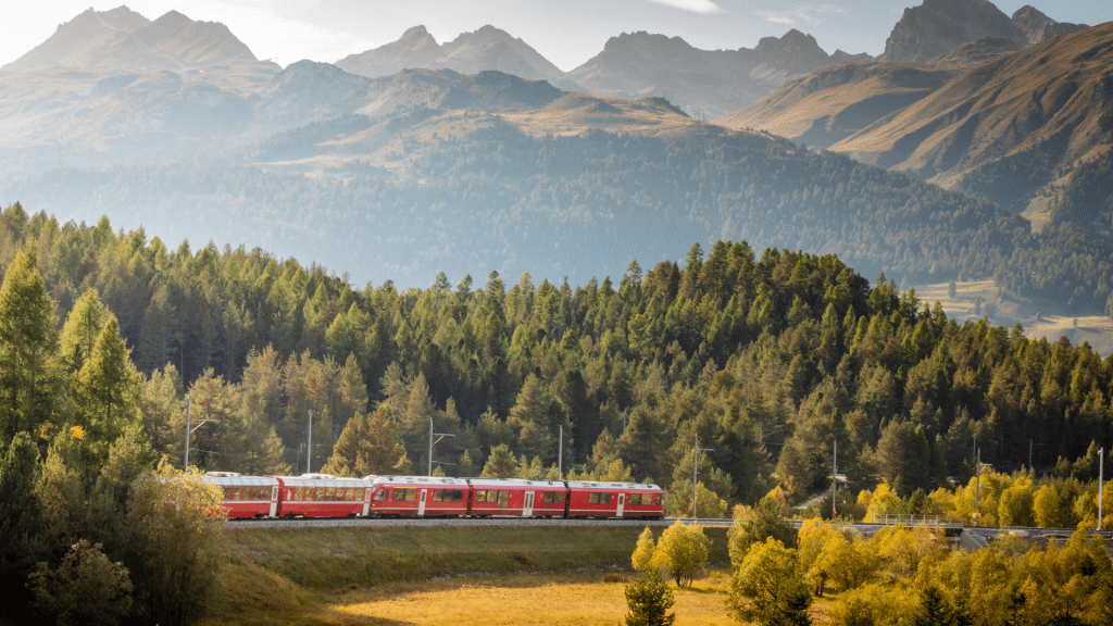 Zug mit viel Natur und Bergen im Hintergrund