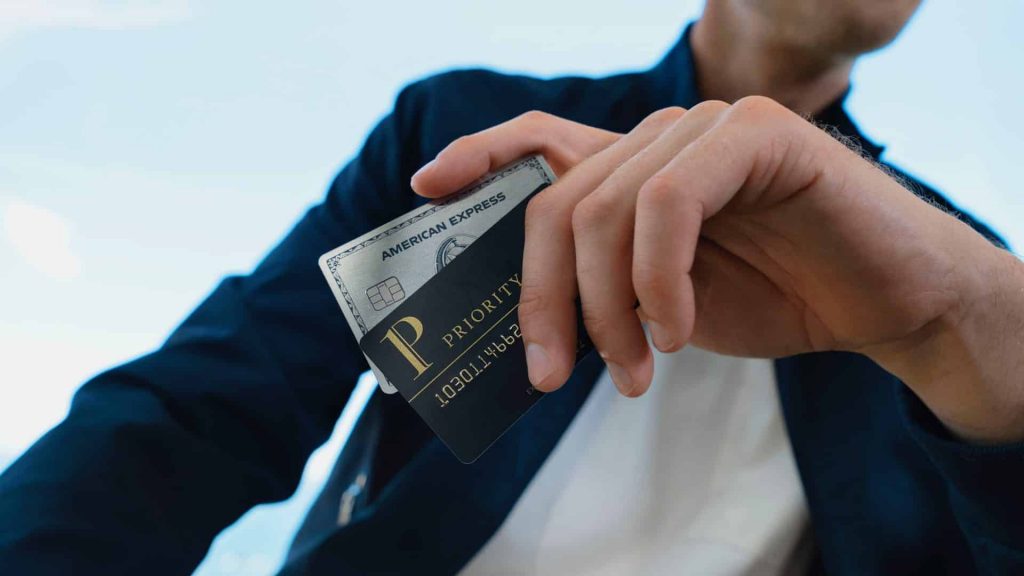 mann haelt Amex Platinum und  Priority Pass in der Hand