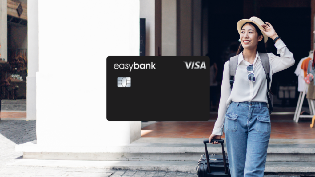 Easybank Visa im Vordergrund, im Hintergrund eine laechelnde Frau mit Sonnenhut und Koffer