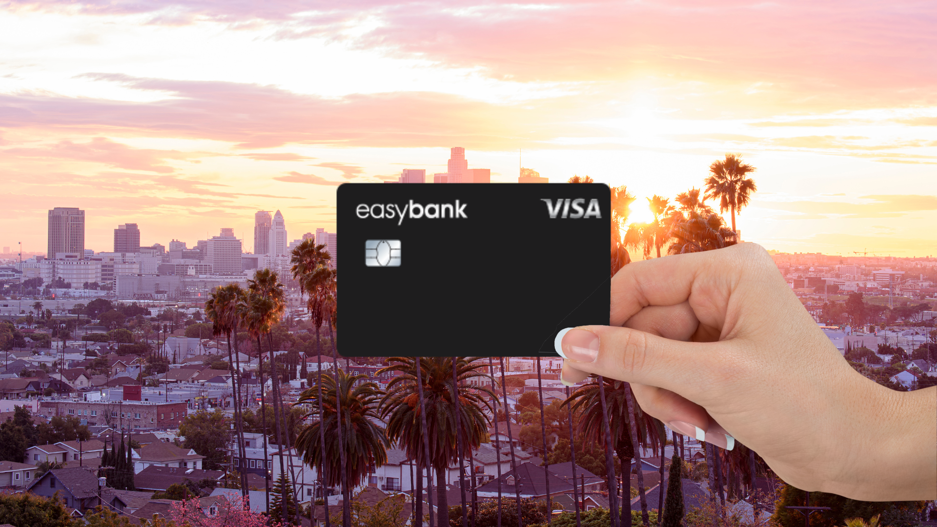 Easybank Visa im Vordergrund, im Hintergrund eine Stadt mit Palmen bei Sonnenuntergang
