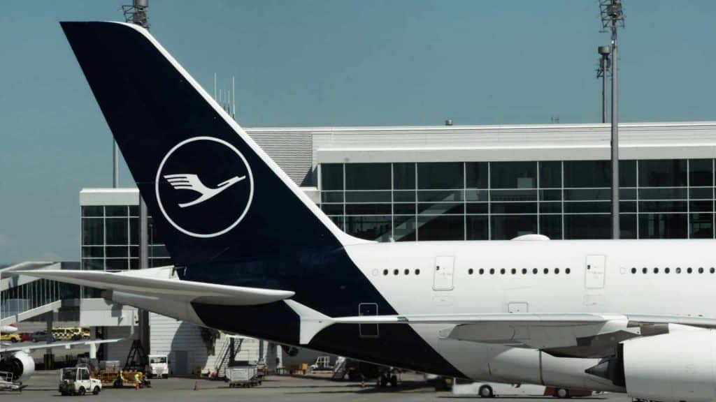 Airbus A380 Tail With Livery Of Lufthansa Airlines At Munich Airport. Big Aircraft Next To Terminal Building And Airport Infrastructure During Sunny Day.