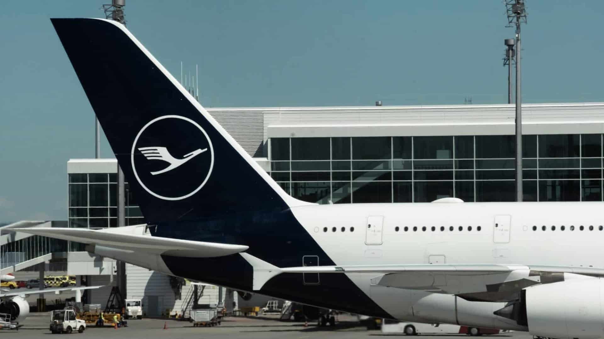 Airbus A380 Tail With Livery Of Lufthansa Airlines At Munich Airport. Big Aircraft Next To Terminal Building And Airport Infrastructure During Sunny Day.