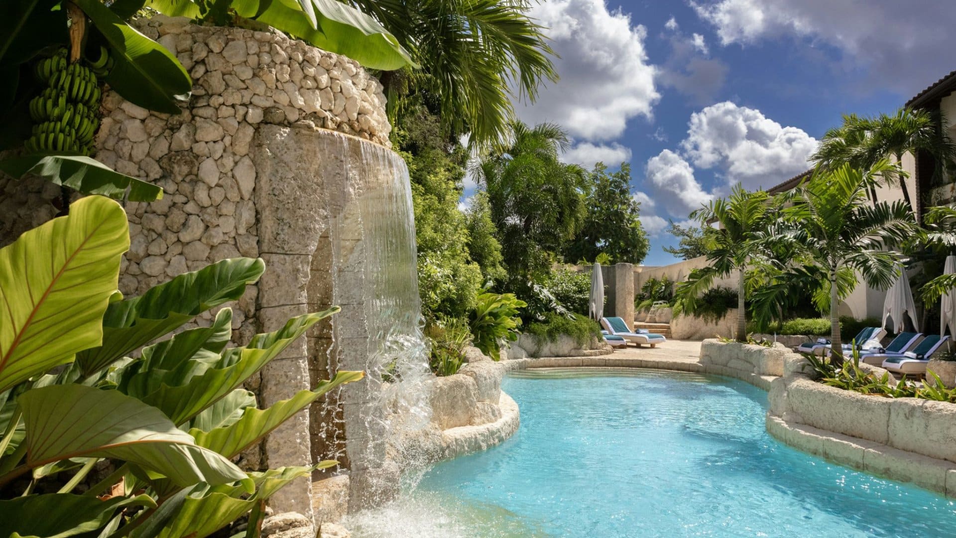 Pool des Blue Monkey Hotel and Beach Club auf Barbados mit Wasserfall ueber einer Steinwand