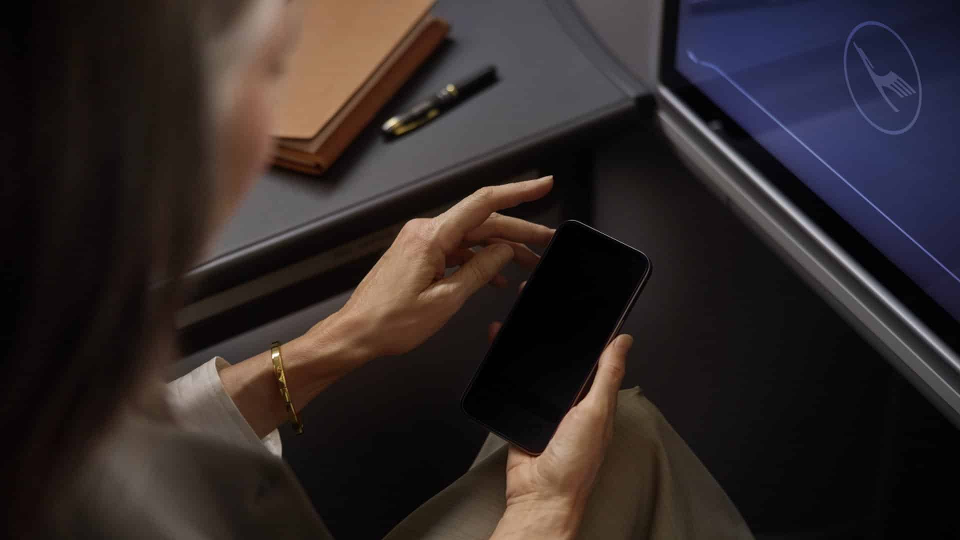 Passagierin nutzt Smartphone an Bord einer Lufthansa Maschine