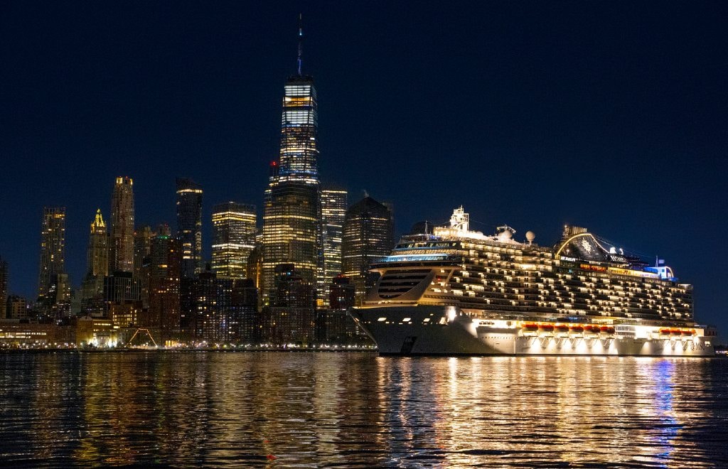 Die MSC Seascape liegt bei Nacht vor der beleuchteten Skyline von New York
