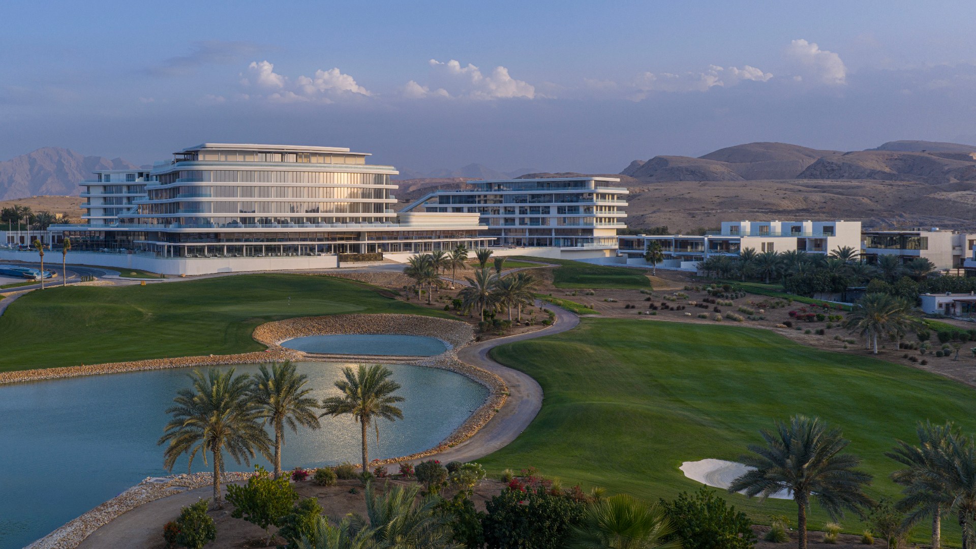 Hotelgebäude des Tivoli LA VIE Muscat mit Golfplatz und Bergkulisse