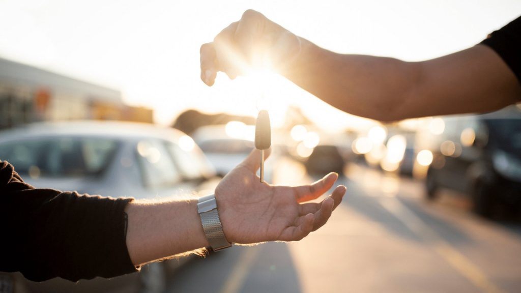 Hand uebergibt einer anderen einen Autoschluessel