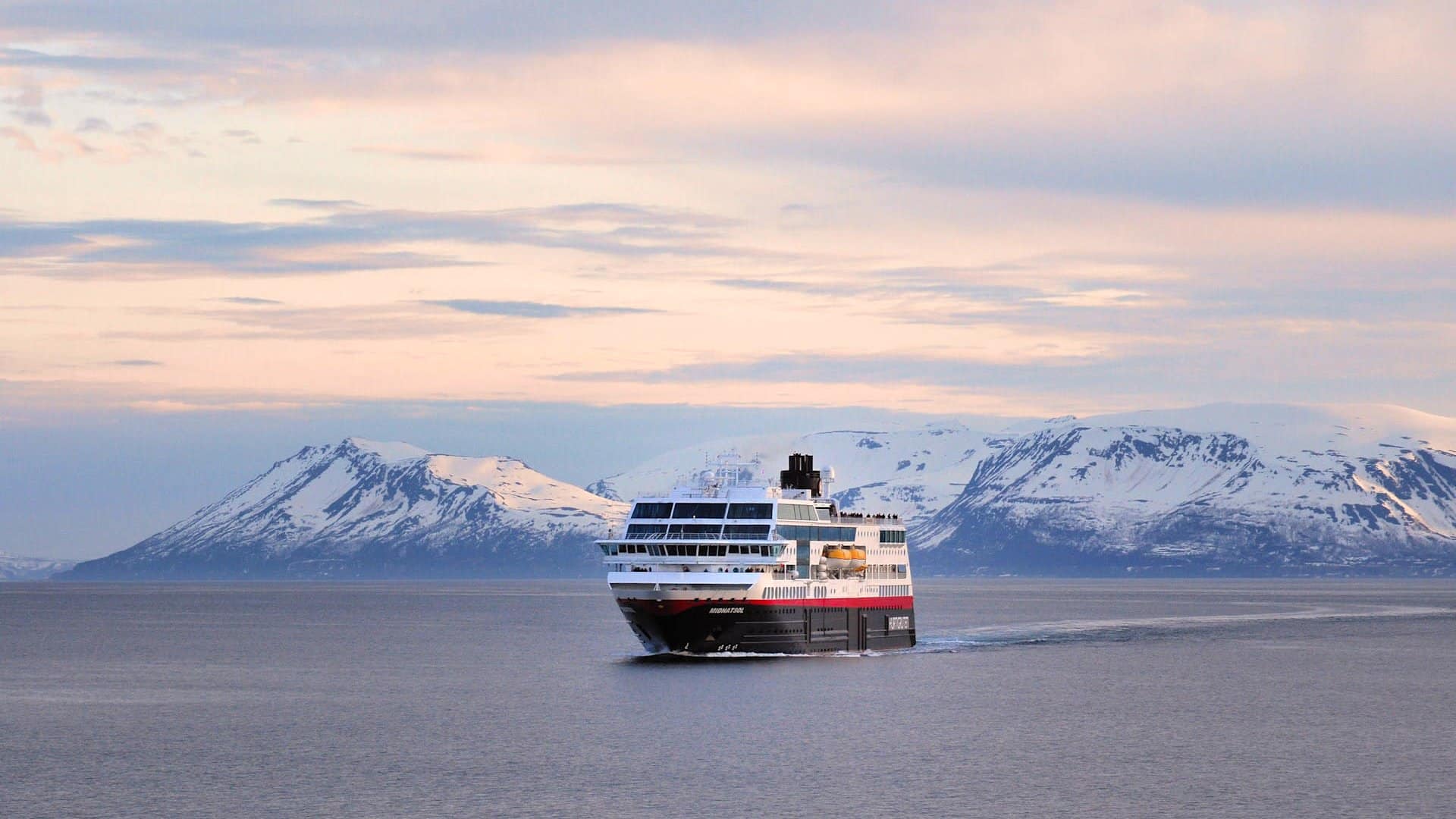 MS Midnatsol von Hurtigruten vor verschneiten Bergen in Norwegen