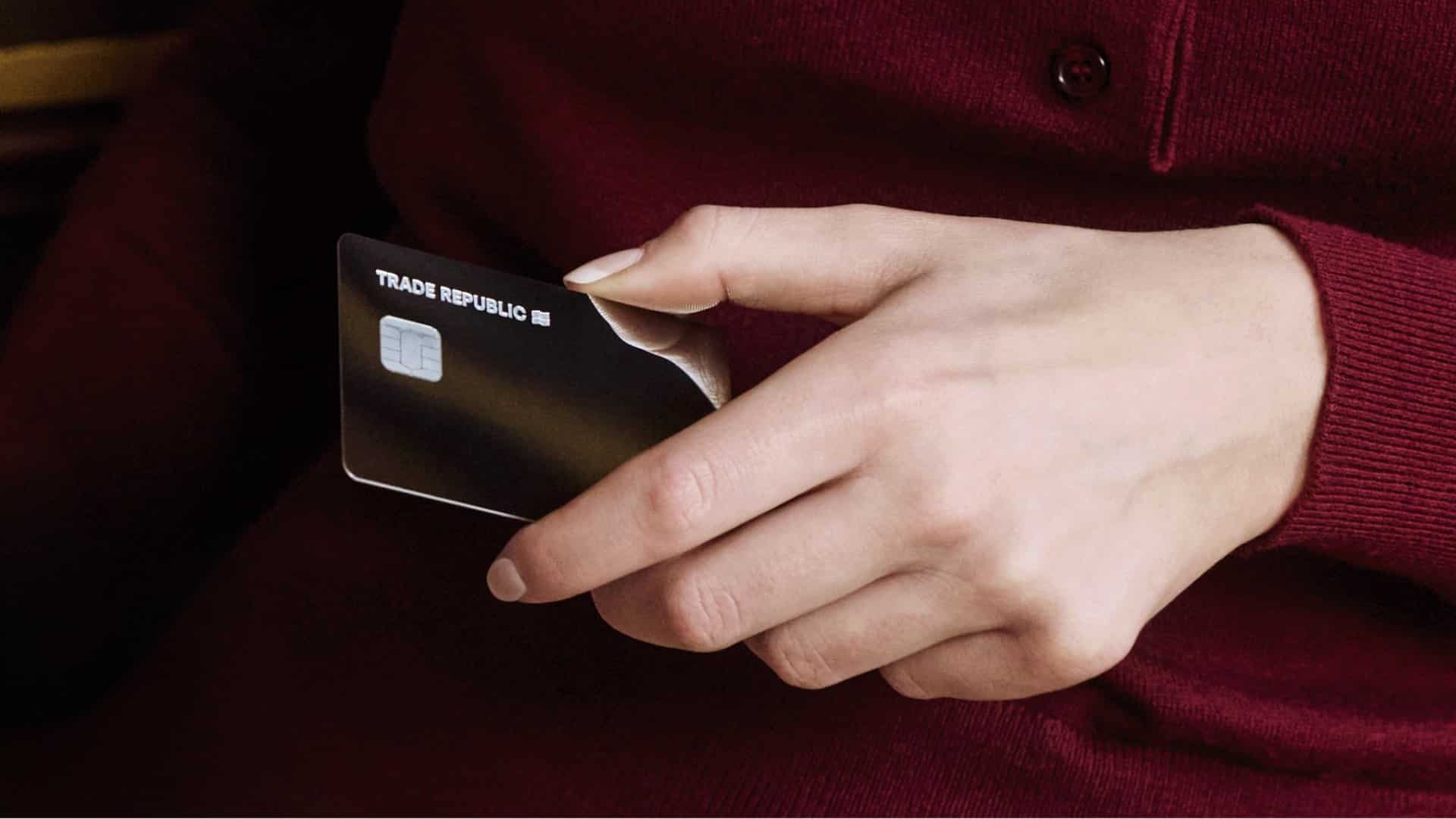Trade Republic Karte in der Hand vor rotem Pullover